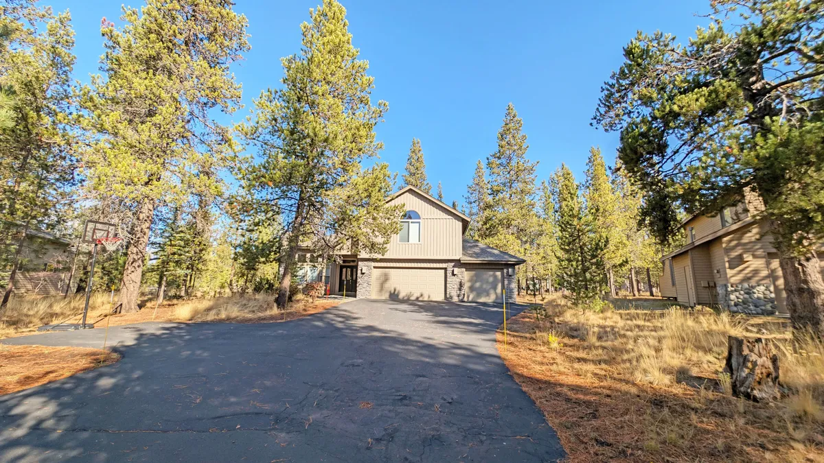 An exterior view of the house showcasing the driveway and surrounding trees, establishing the context for outdoor activities like basketball and biking. The image radiates a welcoming and active vibe, hinting at the adventures awaiting outside the game room.