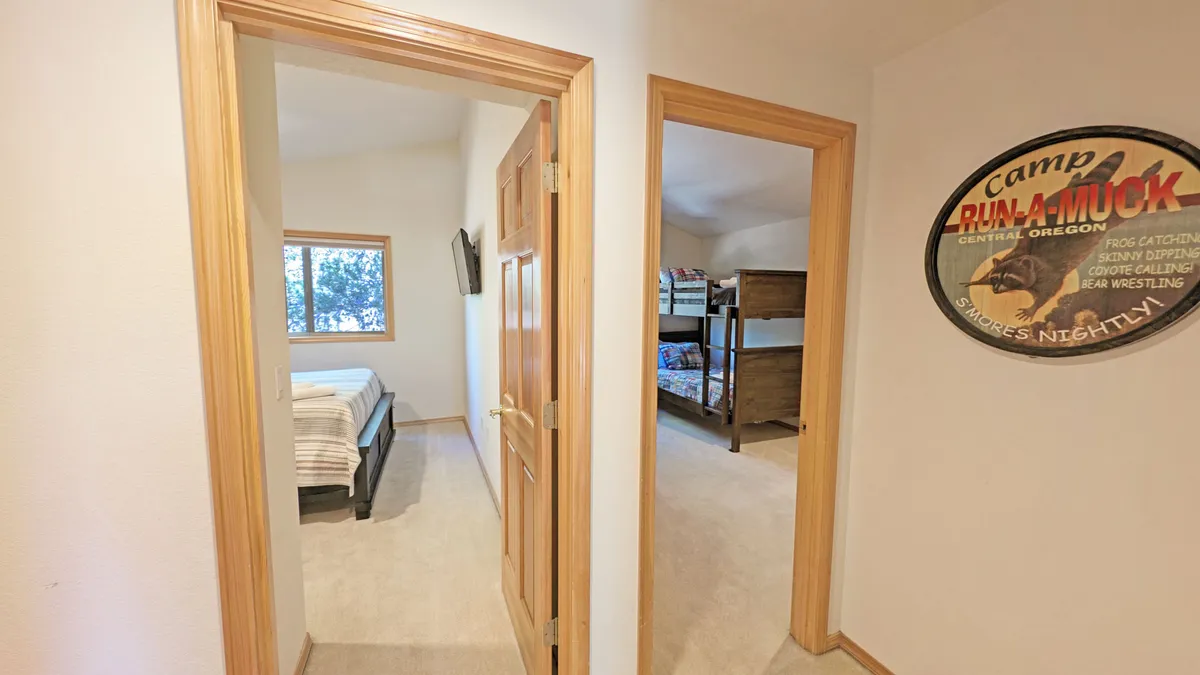 A playful bunk room designed for kids, featuring bunk beds, a single bed, camp-themed wall art, and a window with a scenic view. The room feels fun and comforting, perfectly suited for late-night giggles and storytelling.
