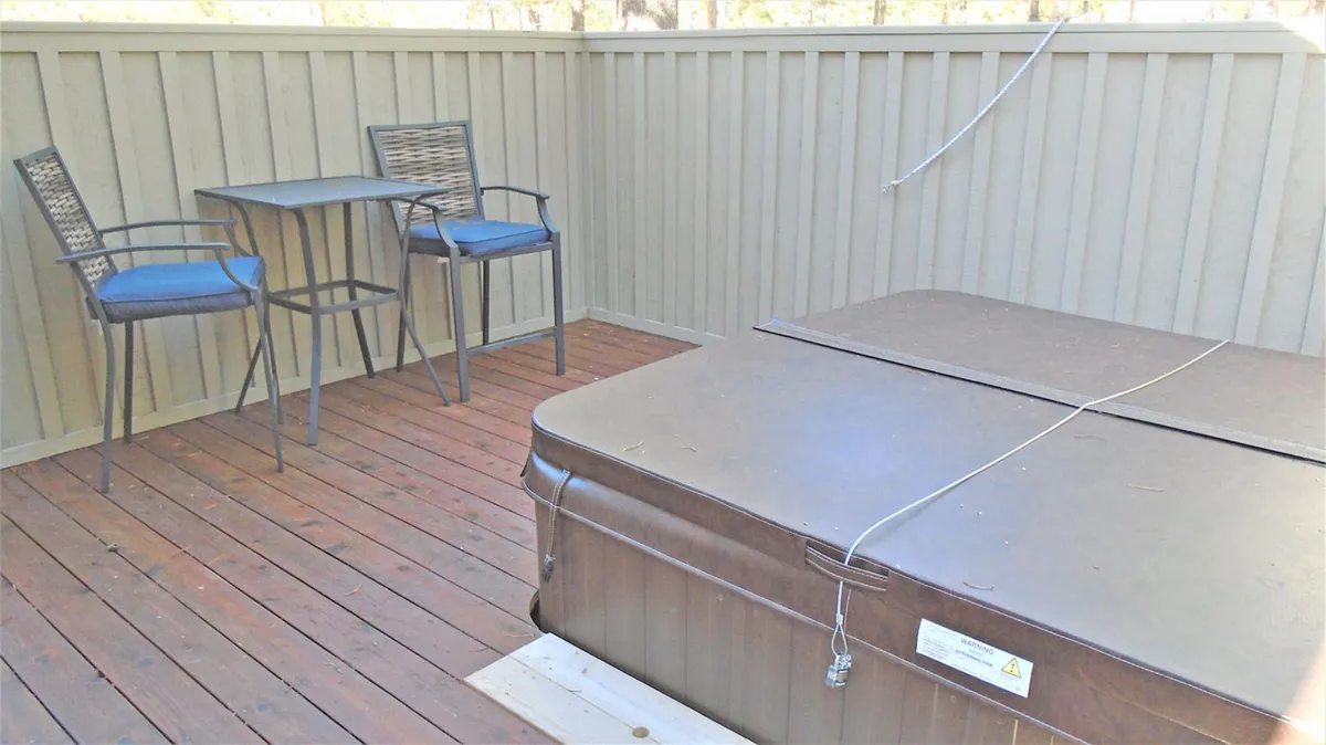 A private hot tub scene with a small table and chairs, set in a serene outdoor environment. The hot tub is inviting and surrounded by nature, suggesting relaxation after a day of activity.