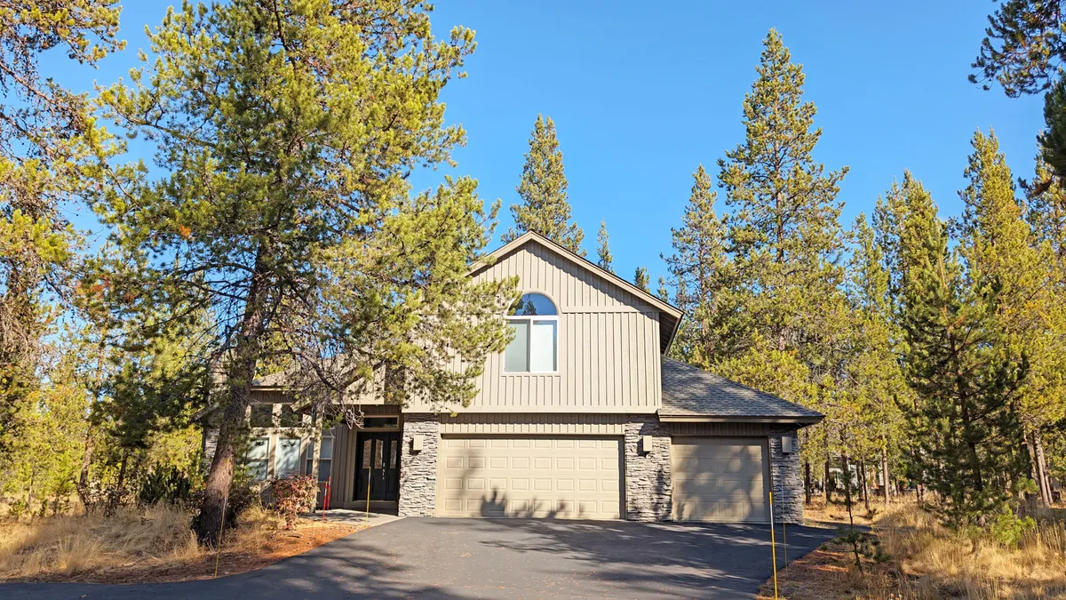 An inviting exterior shot of the home nestled among tall trees, with a spacious driveway and open sky visible above. The setting hints at a peaceful, private retreat perfect for outdoor gatherings and relaxation after a day of adventure.