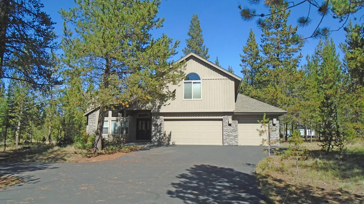 A welcoming exterior view of the Cultus 15 house, surrounded by mature trees and set back from the driveway. The tranquil setting and ample outdoor space suggest both privacy and the potential for group activities or gatherings.